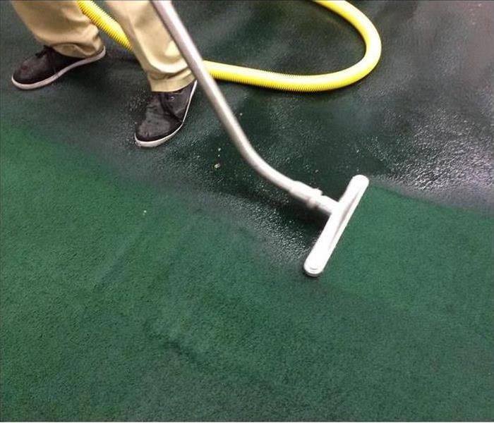 Vaccum extracting water on a green carpet. 